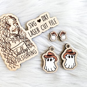 K&ouml;nnte beinhalten: Ein Satz Laser-geschnittener Holzdateien mit einem Geist, der einen Cowboyhut tr&auml;gt. Die Dateien sind mit "SVG &hearts; DXF LASER CUT FILE" und "Shelby Designing" beschriftet.