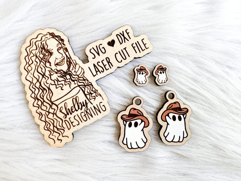 K&ouml;nnte beinhalten: Ein Satz Laser-geschnittener Holzdateien mit einem Geist, der einen Cowboyhut tr&auml;gt. Die Dateien sind mit "SVG &hearts; DXF LASER CUT FILE" und "Shelby Designing" beschriftet.