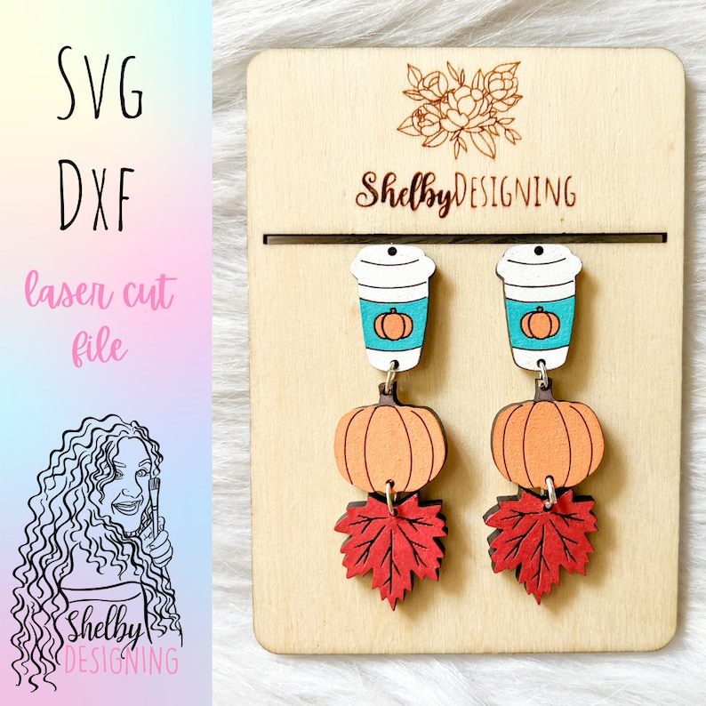 May include: A pair of wooden earrings featuring a pumpkin, a coffee cup with a pumpkin inside, and a red maple leaf. The earrings are displayed on a wooden board with the text "ShelbyDESIGNING".