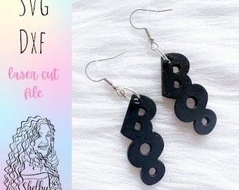 May include: A pair of black laser cut earrings shaped like the word "BOO" hanging from silver earring hooks.