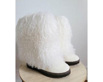 May include: A pair of white, fluffy boots with a shaggy texture. The boots have a white base with a dark brown sole. The boots are displayed on a small, round wooden table.