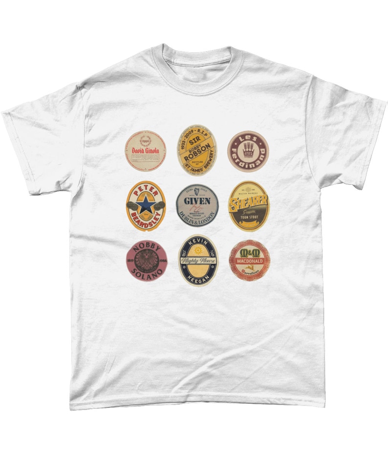 May include: White t-shirt with nine colorful circular patches featuring names like "David Ginola", "Sir Bobby Robson", "Peter Beardsley", "Given", "Shearer", "Nobby Solano", "Kevin Keegan", and "M&D Macdonald".