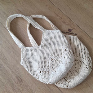 May include: Two crocheted tote bags made of white yarn. The bags have a  pattern of small holes and are made with a  crochet stitch. The bags are lying on a wooden surface.