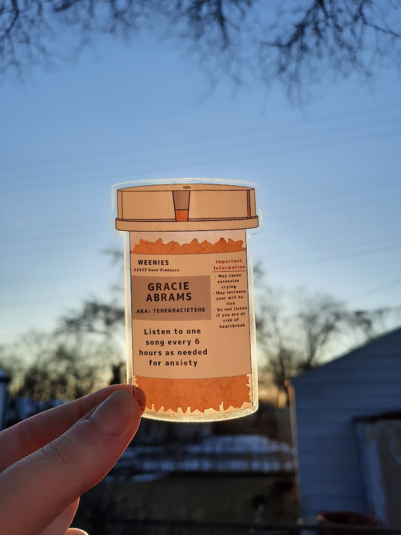 May include: A sticker of a pill bottle with the text "WEENIES 22423 Good Riddance GRACIE ABRAMS AKA: TEHEGRACIETEHE Listen to one song every 6 hours as needed for anxiety Important Information May cause excessive crying May increase your will to live Do not listen if you are at risk of heartbreak"