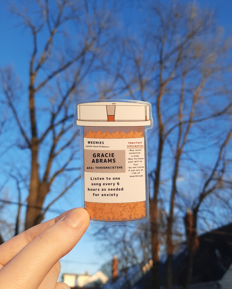 May include: A clear plastic pill bottle sticker with a label that reads "WEENIES 22423 Good Riddance GRACIE ABRAMS AKA: TEHEGRACIETEHE Listen to one song every 6 hours as needed for anxiety Important Information May cause crying May increase your will to live Do not listen if you are at risk of heartbreak"