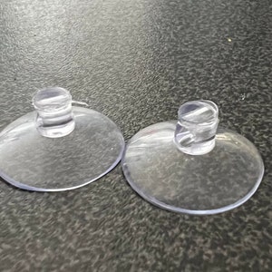 May include: Two clear plastic suction cups with a raised centre. The suction cups are designed to be used for hanging items.
