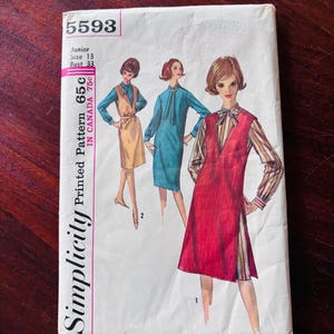 May include: A Simplicity sewing pattern envelope, number 5593, for a junior size 13 with a 33-inch bust. The front features illustrations of three outfits: a red sleeveless dress over a striped blouse, a teal dress, and a tan sleeveless dress.