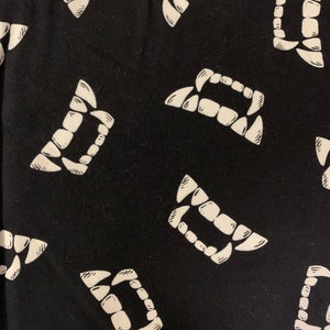 May include: Black fabric with a white repeated pattern of vampire fangs.