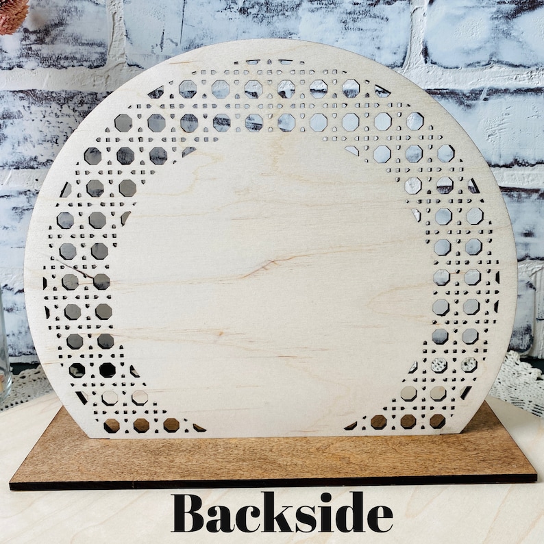 May include: A wooden cutout of a half-circle with a decorative pattern of small circles and squares. The cutout is on a wooden base with the word "Backside" printed on it.