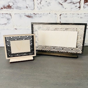 May include: Two wooden picture frames with a black and white wave pattern. The frames are blank and ready for a photo or message.