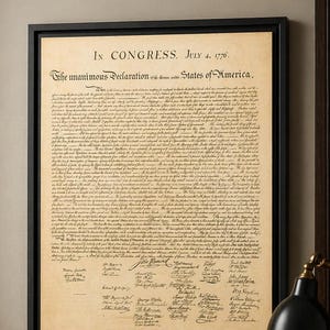 May include: A framed canvas print of the Declaration of Independence, featuring the text "In Congress, July 4, 1776." The document is displayed in a black frame, with the text in a vintage style. The print is on a desk with books and a lamp.