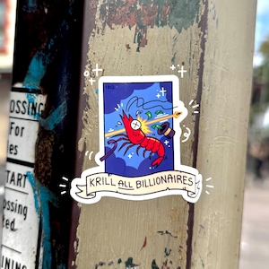 May include: A sticker with a cartoon illustration of a red shrimp with a target on its head. The shrimp is holding a dollar bill and a top hat. The sticker has the text "Krill All Billionaires" on a banner.