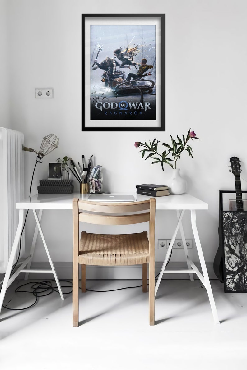 Op de afbeelding: Een zwart ingelijste poster met een blauwe en witte illustratie van drie figuren op een slee. De poster heeft de tekst "God of War Ragnar&ouml;k" in witte letters.