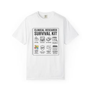 May include: A white short-sleeve t-shirt featuring a black graphic box labeled Clinical Research Survival Kit. The design includes icons for caffeine, data entry, the protocol, pivot tables, sticky notes, GCP, bubbles, and a calendar with text.