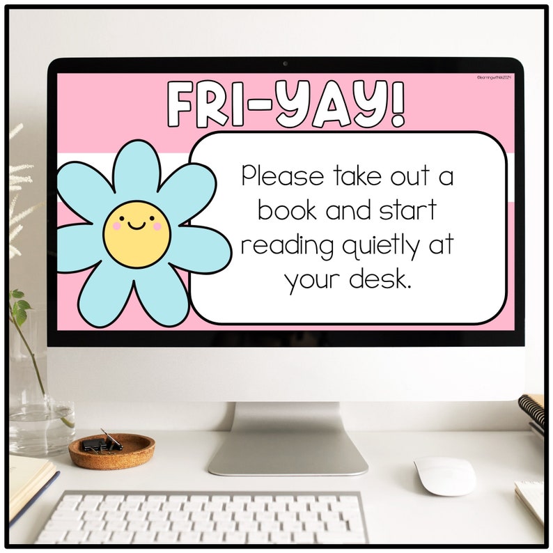 May include: A computer screen displaying a pink and white background with a blue flower graphic. The text on the screen reads "FRI-YAY! Please take out a book and start reading quietly at your desk."