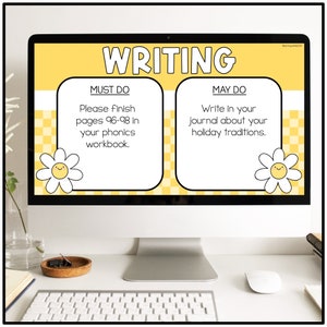 May include: A computer screen displaying a yellow and white writing assignment for students. The screen shows two sections, "Must Do" and "May Do". The "Must Do" section instructs students to finish pages 96-98 in their phonics workbook. The "May Do" section instructs students to write in their journal about their holiday traditions.