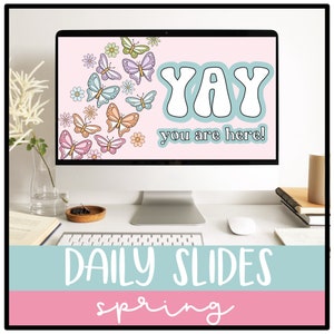 Op de afbeelding: Een computerscherm met een roze achtergrond waarop de tekst "YAY you are here!" staat in een blauw en wit lettertype. Het scherm is omgeven door een witte rand en staat op een wit bureau. Het scherm is versierd met kleurrijke vlinders en bloemen. De tekst "DAILY SLIDES spring" wordt weergegeven op een blauwe en roze achtergrond onder het computerscherm.