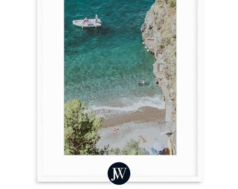May include: An aerial view of a rocky coastline with a small boat in the turquoise water. The beach is covered in pebbles and there are people swimming in the water.