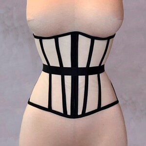 May include: A white corset with black elastic straps. The corset has a boned structure and a smooth, satin-like finish.