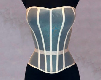 Puede incluir: Un corsé blanco de malla con costuras verticales y un diseño sin tirantes. El corsé está en un maniquí negro.