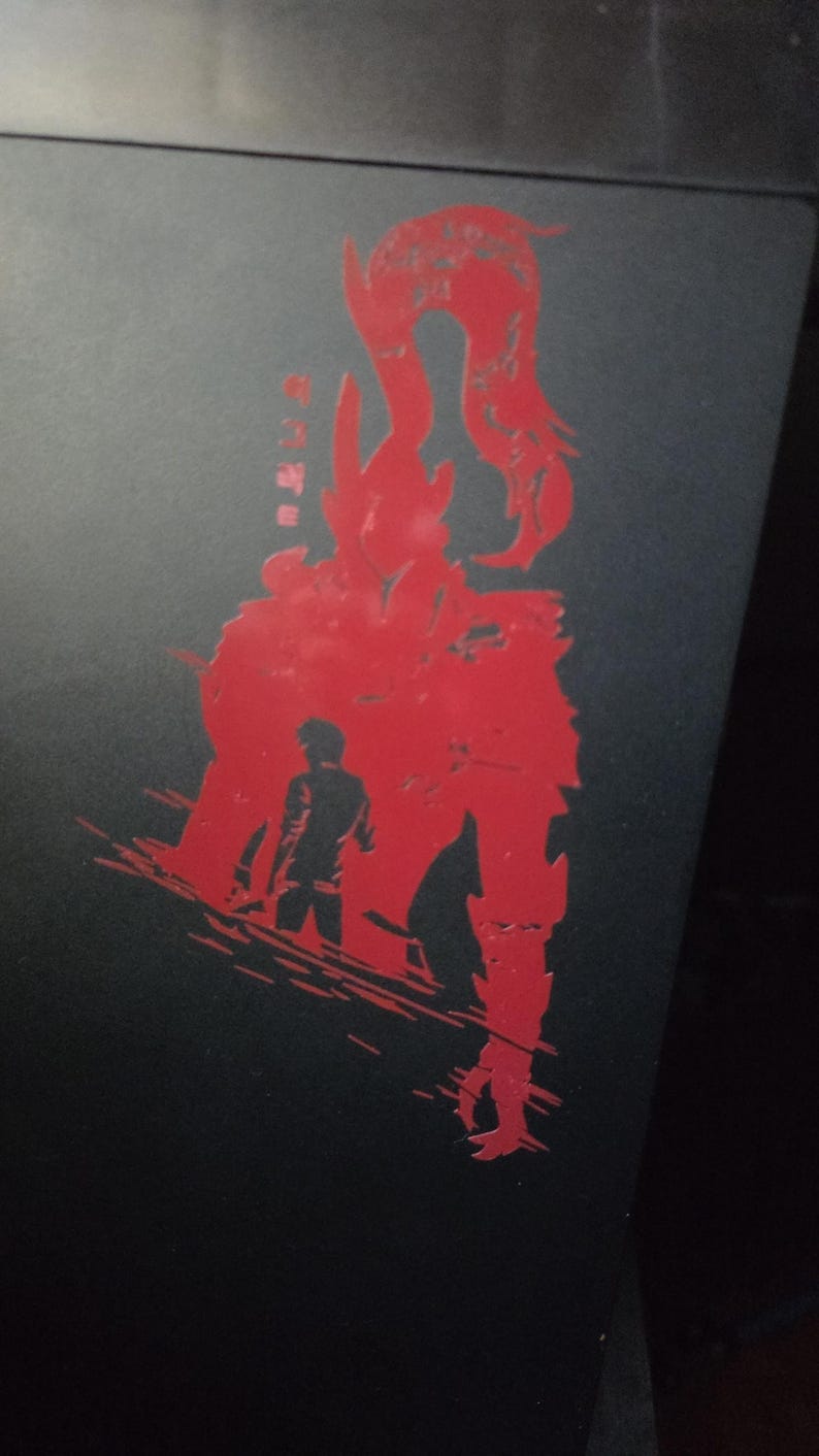 May include: Black surface with a red graphic design featuring a silhouette of a figure and a monster. Japanese text is visible on the left side of the image. The design has a distressed, textured appearance.