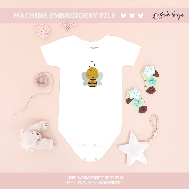 May include: White baby onesie with a cartoon bee design. The bee is yellow, black, and brown with light blue wings. The image also includes star-shaped socks, a white star, and the text "MACHINE EMBROIDERY FILE".