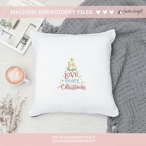 May include: White square pillow with a black trim, embroidered with a Christmas tree design. The tree is composed of the words "Joy, hope, LOVE, PEACE, Christmas" in various colors. The words are arranged in a tree shape.