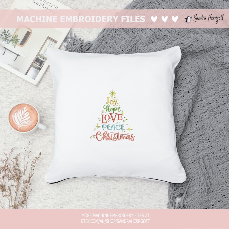 May include: White square pillow with a black trim, embroidered with a Christmas tree design. The tree is composed of the words "Joy, hope, LOVE, PEACE, Christmas" in various colors. The words are arranged in a tree shape.
