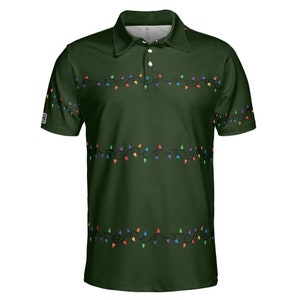 May include: Dark green polo shirt with a festive design. The shirt features a pattern of colorful string lights across the chest and sleeves. It has a collared neckline and three white buttons.