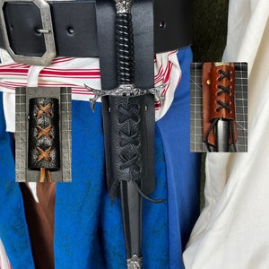 May include: A black leather scabbard with a black and silver dagger. The scabbard has a laced closure and is worn on a black belt.
