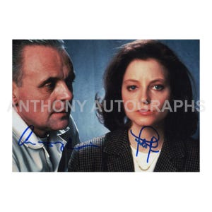 Peut inclure: Photographie de deux personnes, un homme et une femme, avec des signatures à l'encre bleue. L'homme porte une chemise blanche à col, et la femme un blazer à motifs noirs et gris. Le texte "ANTHONY AUTOGRAPHS" est visible.