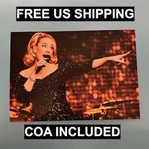 Puede incluir: Fotografía de una cantante en el escenario, sosteniendo un micrófono y señalando. La cantante lleva un vestido negro con lentejuelas. La imagen incluye el texto "COA INCLUDED".