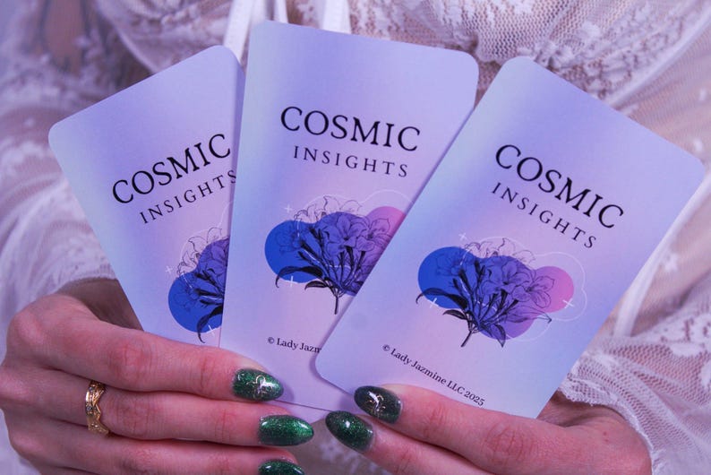 May include: Three Cosmic Insights cards are held in a person's hands. The cards have a lavender background with the words "COSMIC INSIGHTS" in black. Each card features a blue and purple floral design. The copyright reads "Lady Jazmine LLC 2023".
