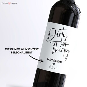 May include: A white wine bottle label with black text that reads "Dirty Thirty Happy Birthday" with a small heart symbol and the name "Sabrina".