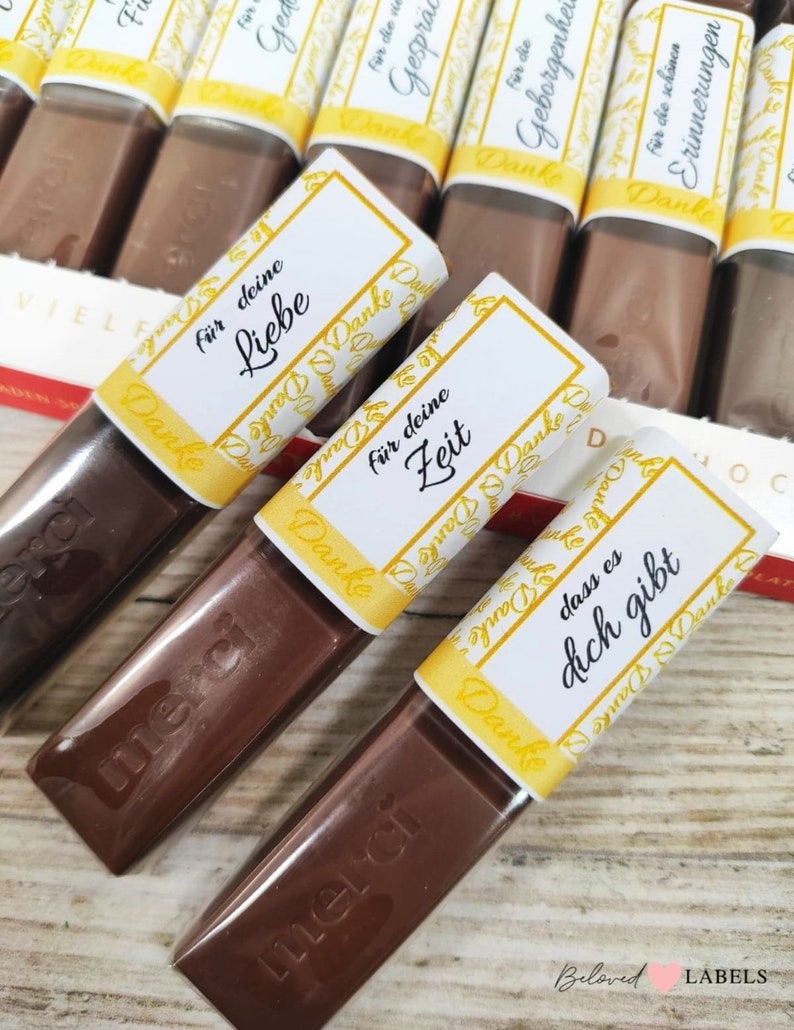 May include: Assortment of small chocolate bars wrapped in clear plastic with yellow and white labels. The labels have the word "Danke" and various German phrases, including "f&uuml;r deine Liebe", "f&uuml;r deine Zeit", and "dass es dich gibt".