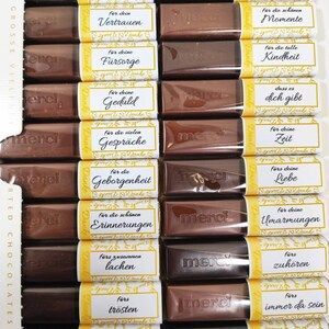 May include: A box of chocolate bars with yellow and white labels. Each label has a different message of thanks in German. The messages include "Vertrauen", "F&uuml;rsorge", "Geduld", "Gespr&auml;che", "Geborgenheit", "Erinnerungen", "Lachen", "Tr&ouml;sten", "Momente", "Kindheit", "Dich gibt", "Zeit", "Liebe", "Umarmungen", "Zuh&ouml;ren", "Immer da sein".