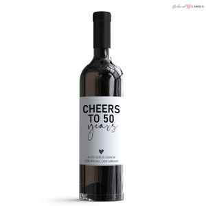 May include: A white wine bottle label with black text that reads "Cheers to 50 years" and "Alles Gute zu deinem Geburtstag, Liebe Miriam!" with a small black heart.