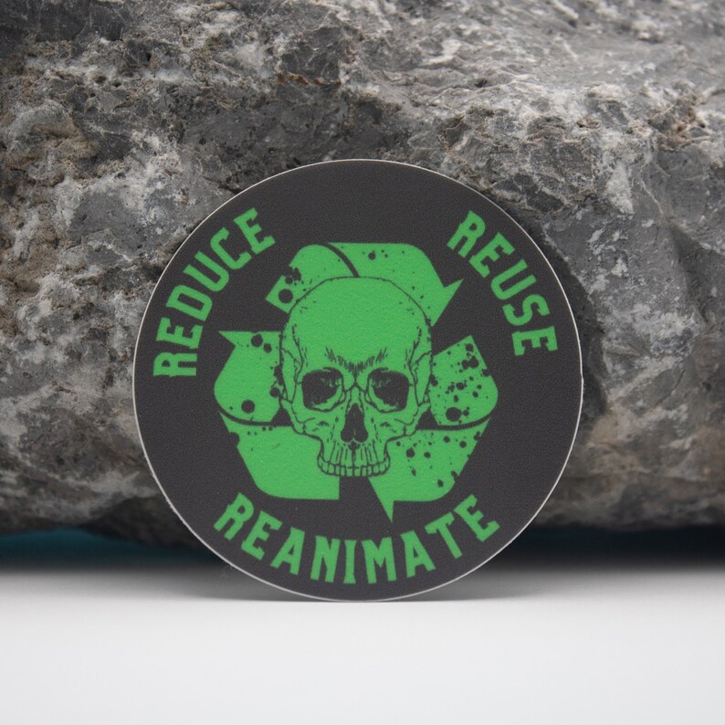 May include: A black and green round sticker with a recycle symbol and the words "Reduce Reuse Reanimate" around the symbol. A green skull is in the center of the symbol.