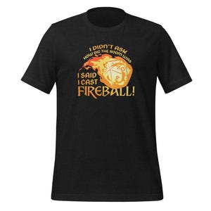 May include: Dark gray t-shirt with the text "I DIDN'T ASK HOW BIG THE ROOM WAS, I SAID I CAST FIREBALL!" in orange and white. The graphic features a flaming fireball with a die inside.