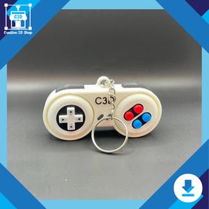 Black and gray 3D printed retro gamepad fidget keychain on desk surface