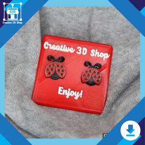 Printable ladybug earrings made from STL file, sitting on a product card