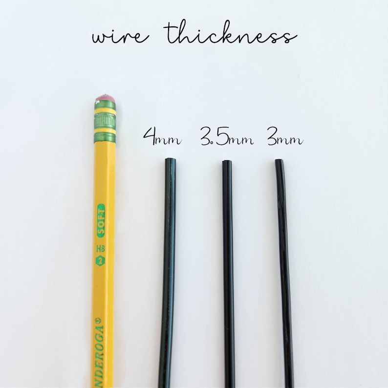 Op de afbeelding: Een gele potlood met een roze gum naast drie zwarte draden van verschillende diktes: 4 mm, 3,5 mm en 3 mm. De tekst "wire thickness" staat boven de draden. Het potlood is gemarkeerd met "ENDEROGA".
