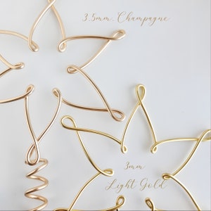 May include: Close-up of six gold wire shapes, three are 3.5mm Champagne and three are 3mm Light Gold. The wire shapes are twisted into a decorative design.