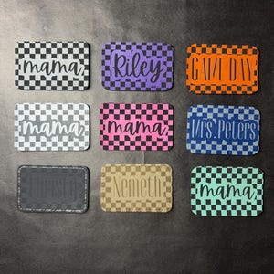 May include: Nine rectangular patches with rounded corners, each featuring a checkered pattern in various colours including black, purple, orange, white, pink, blue, grey, tan, and teal, with custom text like mama, Riley, GAME DAY, and Mrs. Peters.