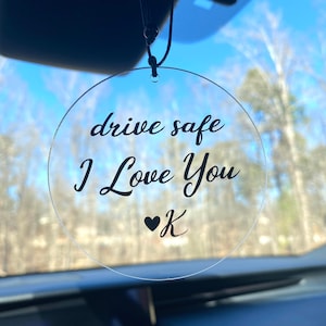 May include: A clear round car charm with the text "drive safe I Love You ♥ K" printed in black.