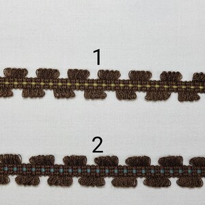 May include: Two brown trim samples with scalloped edges. The top sample has a yellow stripe in the center. The bottom sample has a blue stripe in the center. The samples are labeled "1" and "2".