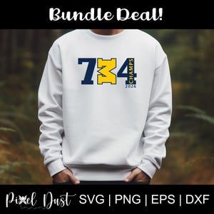 Op de afbeelding: Witte sweatshirt met een marineblauwe en gele opdruk met de tekst "734 Champs 2026". De sweatshirt heeft lange mouwen en een ronde hals. De woorden "Bundle Deal!" staan bovenaan de afbeelding.