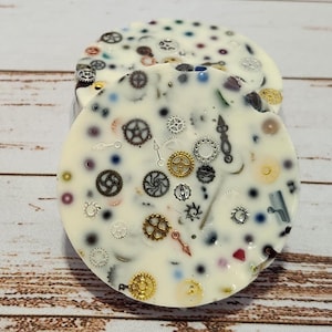 May include: Two white chocolate discs with a variety of colourful and metallic watch parts embedded in the chocolate.