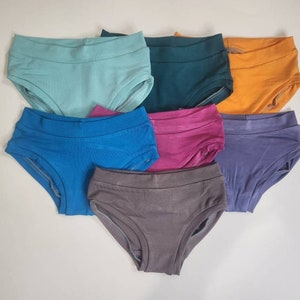 May include: Seven pairs of underwear in different colors, including teal, blue, purple, pink, gray, orange, and green.