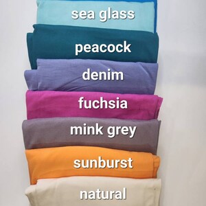 May include: A stack of eight fabric swatches in different colors, including turquoise blue, sea glass, peacock, denim, fuchsia, mink grey, sunburst, and natural.